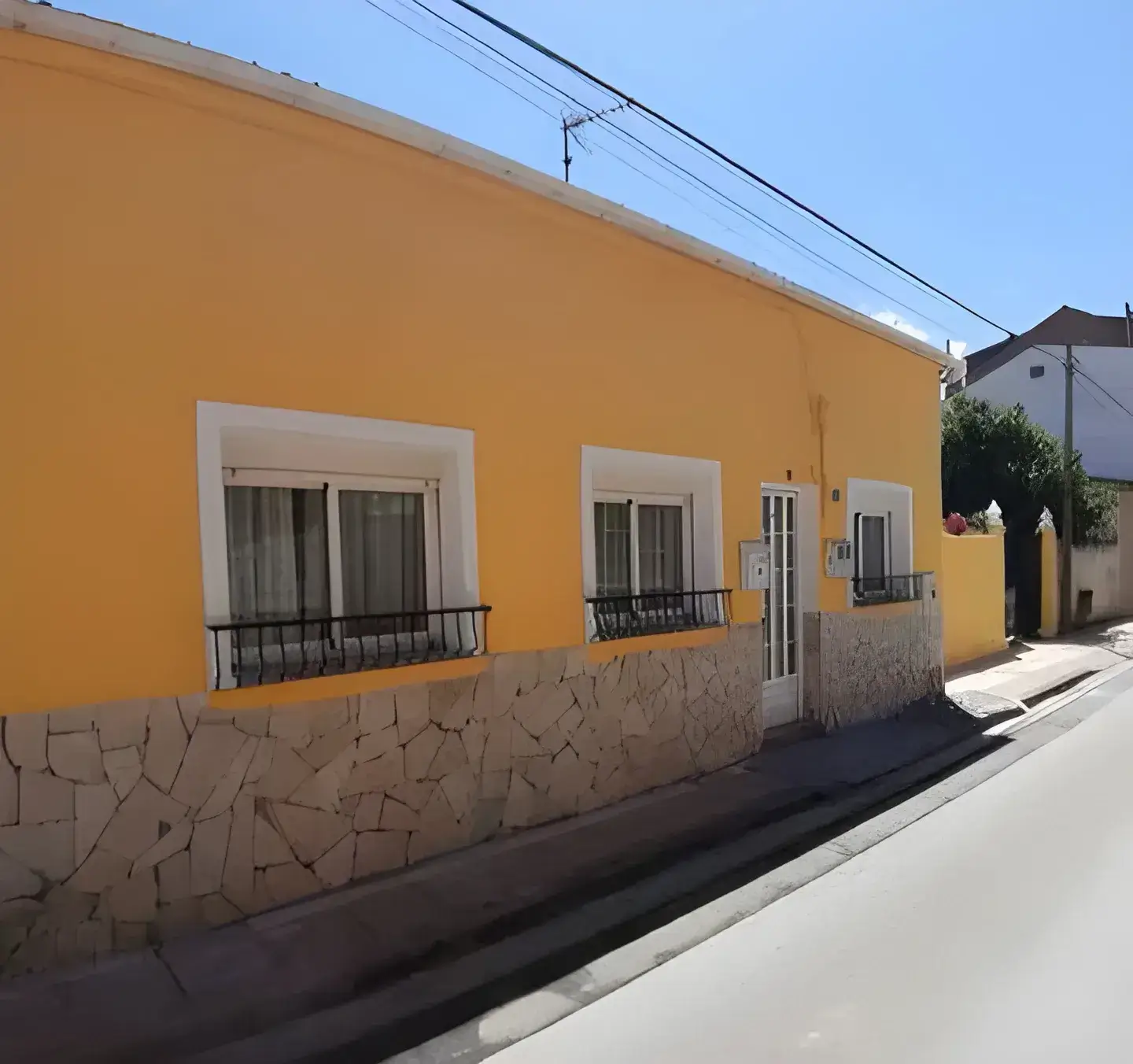 Los Pintores Alcala de Henares Fachada de casa tradicional pintada en color amarillo con zócalo de piedra
